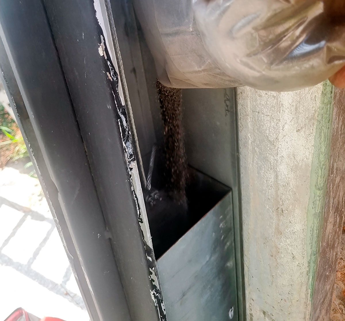Técnico realizando balanceamento de portão basculante com adição de material na caixa de contrapeso em Itaquera